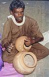 A blind beggar playing on the earthen pots