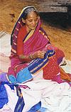 A grand-mother engrossed in stitching a quilt