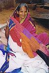 A grand-mother engrossed in stitching a quilt