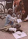 A blind street beggar plays flute through his nose, Bangalore