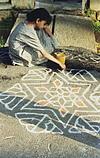 a girl drawing rangoli