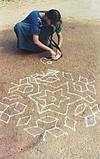 a girl drawing rangoli