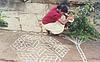 a girl looking in to a book and  drawing rangoli