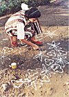 This school girl wears colorful dresses to draw her rangoli.