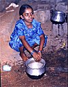 A Young Girl Washing Dishes by the Roadside