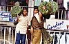 Boys selling fans made with peacock feathers on pavement